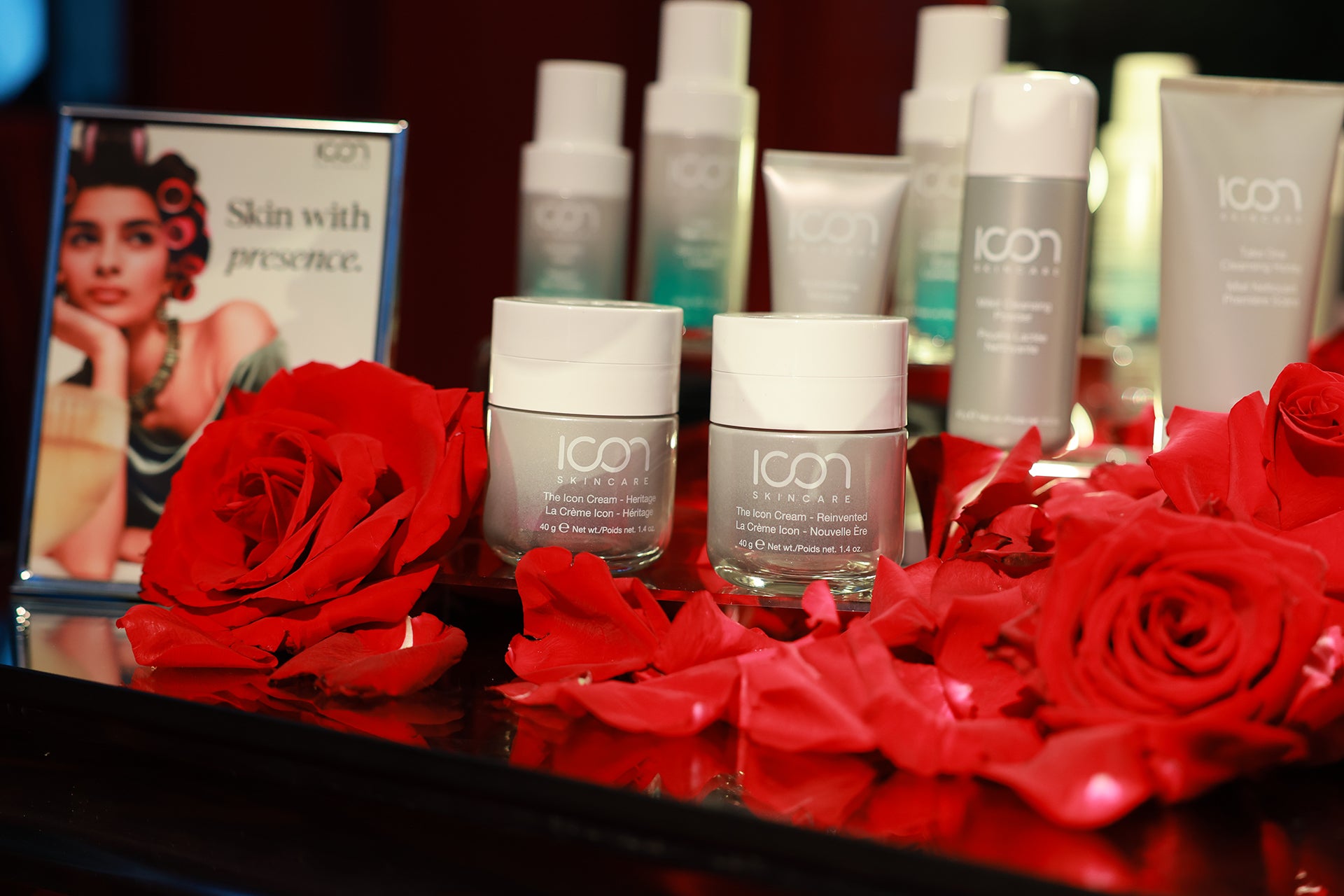 Icon skincare products with red roses on a reflective surface